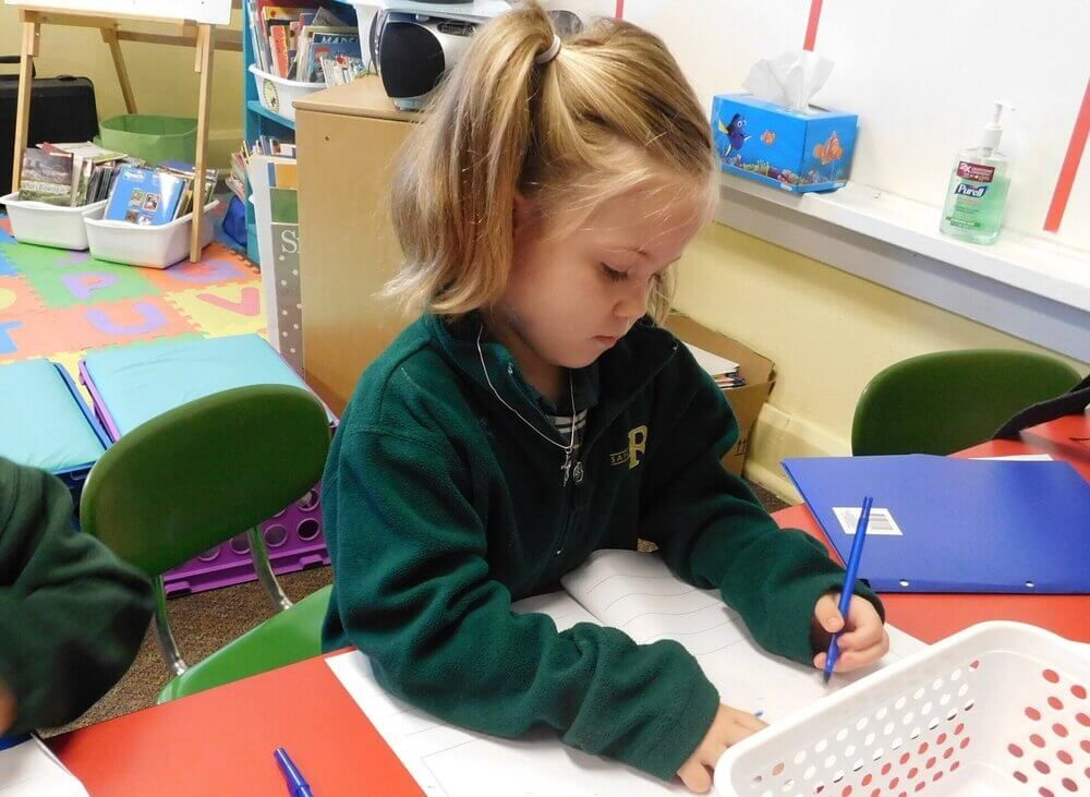 Student writing at a desk during writers workshop