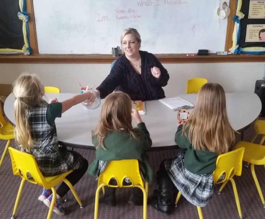Students sitting around a table with a teacher.